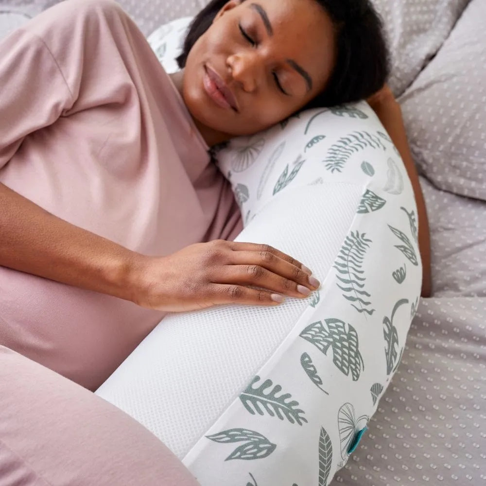 Woman sleeping comfortably with the Purflo Breathe Pregnancy Pillow in Jardin print, providing ergonomic support.