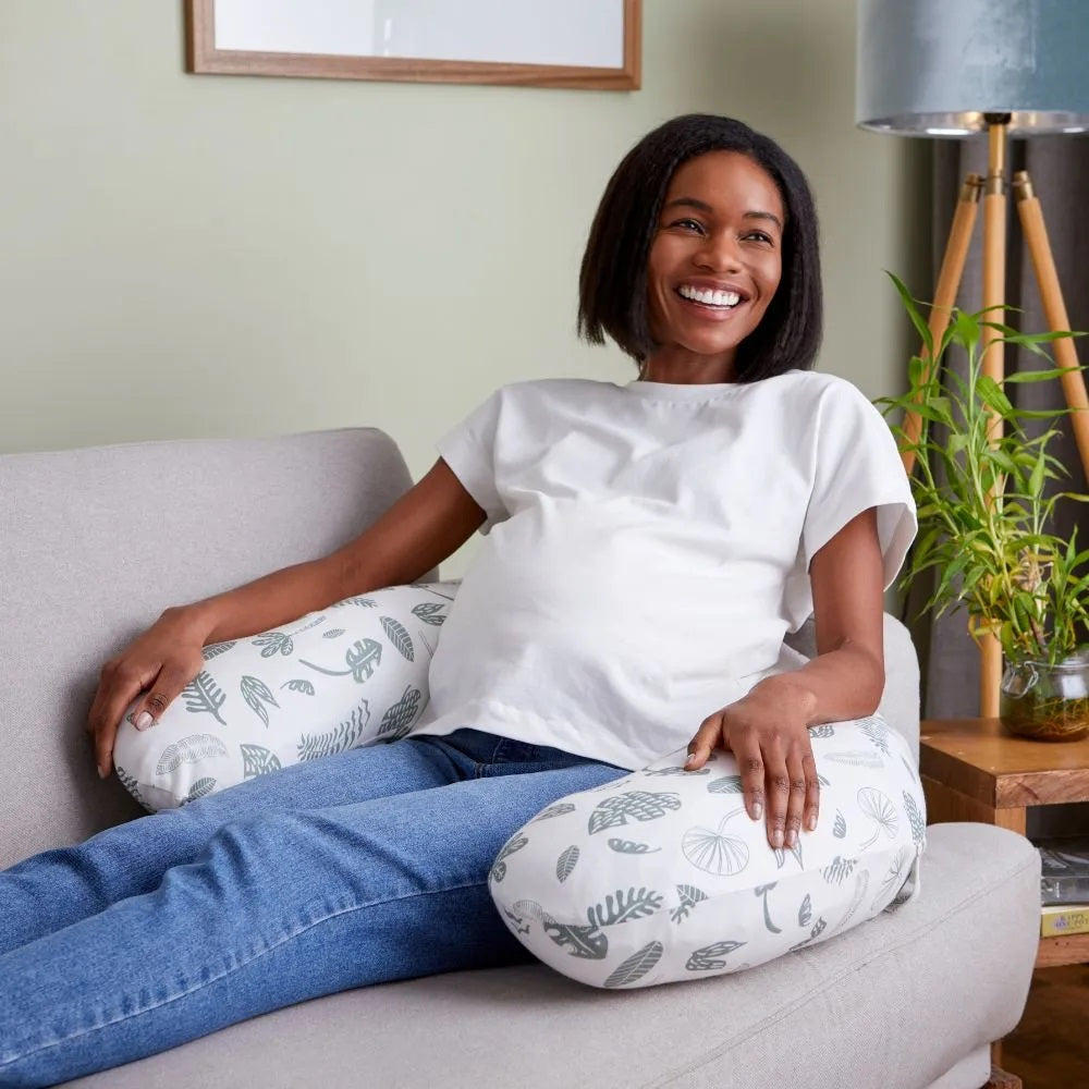 Pregnant woman relaxing on a sofa with the Purflo Breathe Pregnancy Pillow in Jardin print, providing ergonomic support and comfort.