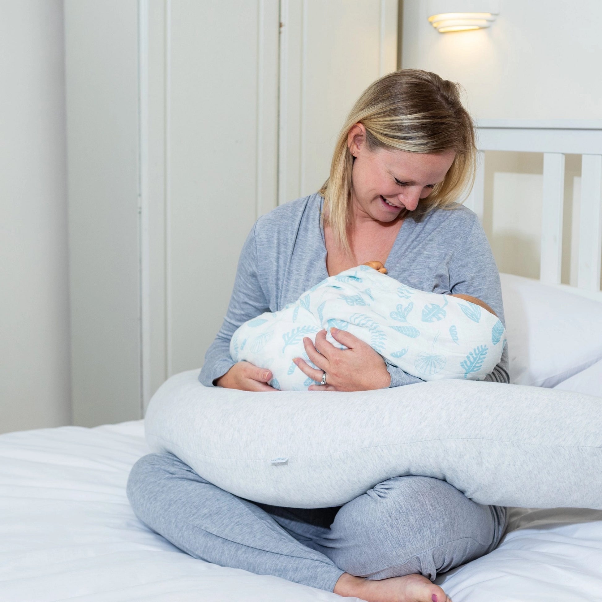 Mother using the Purflo Breathe Pregnancy Pillow in minimal grey for breastfeeding, offering comfortable support and positioning for baby.