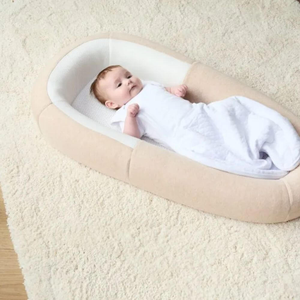 Baby resting comfortably in the Purflo Sleeptight Baby Bedl. Breathable mesh base and soft sides offer safety, support, and relaxation.