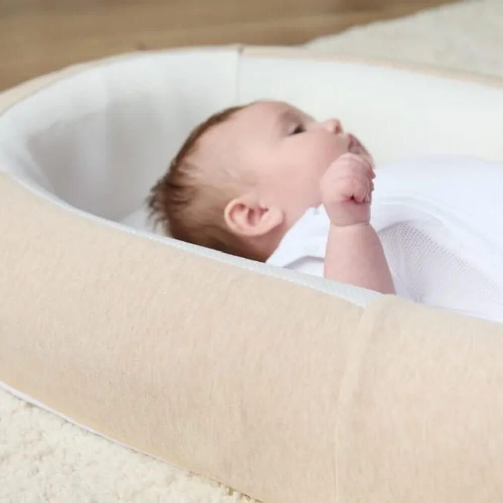 Close-up of baby resting in the Purflo Sleeptight Baby Bed. Soft padded sides and breathable mesh base ensure comfort and safety.