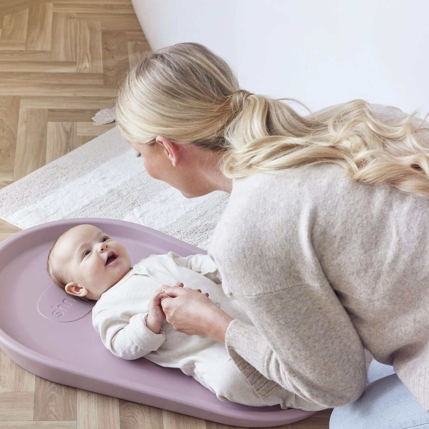 Mother interacting with happy baby on Shnuggle Squishy Change Mat, showcasing comfortable height and supportive design during nappy changes.