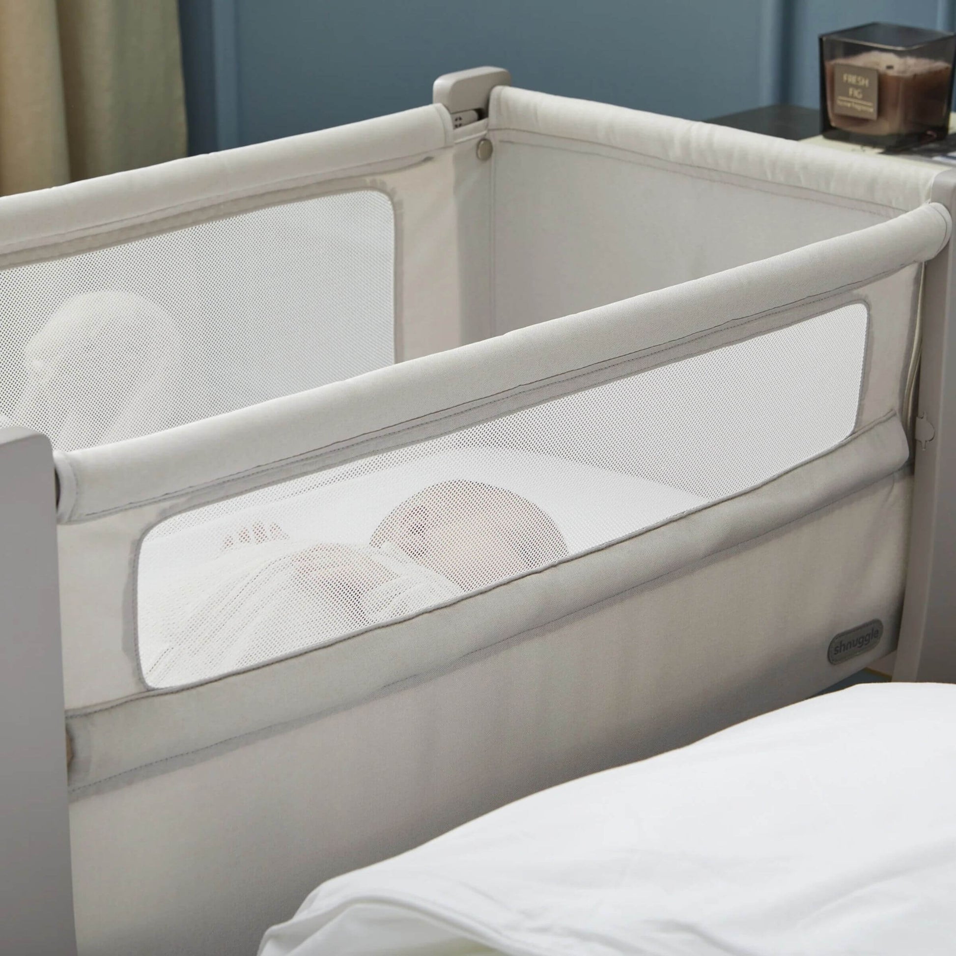 Baby sleeping peacefully in Shnuggle Air Lite Bedside Crib with breathable mesh sides, ensuring visibility and airflow.