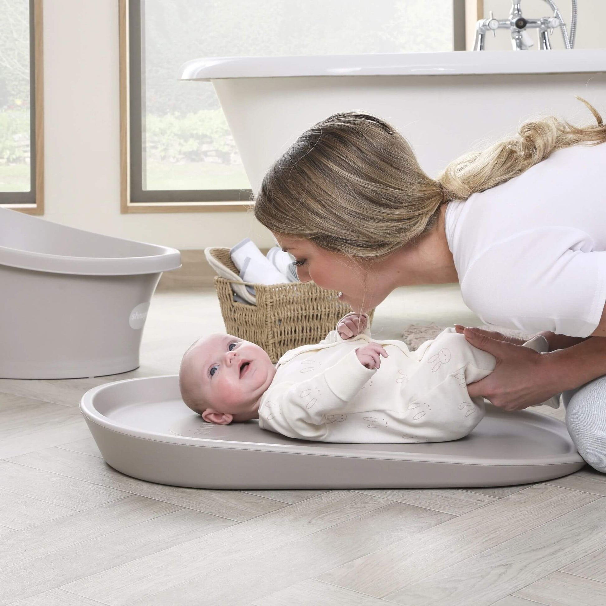 Mother smiling at baby on Shnuggle Squishy Changing Mat in taupe, creating a warm and playful moment during nappy changing.