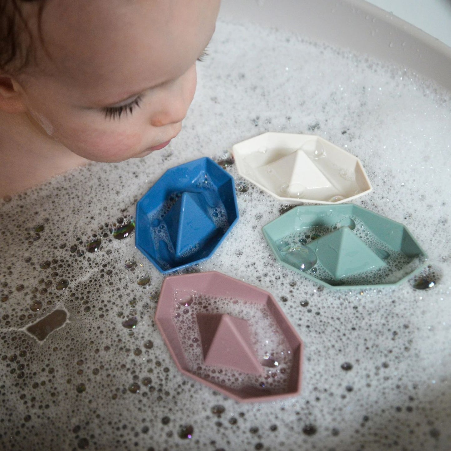 Child watching Shnuggle Stack ‘n’ Sail Bath Boat floating on bubbly bath water, enjoying playful bath time.