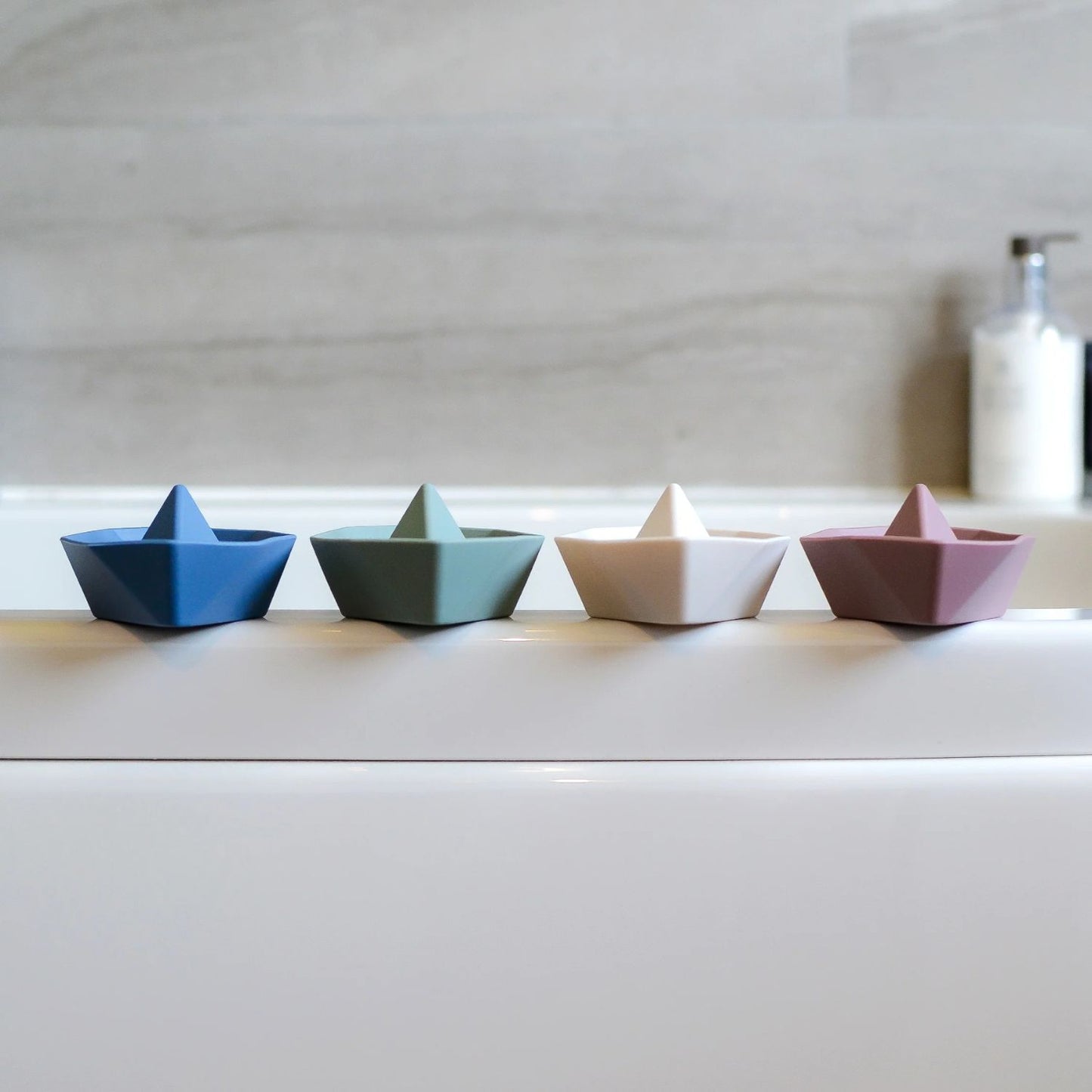 Four Shnuggle Stack ‘n’ Sail Bath Boat Toys lined up on the edge of a bathtub, adding a playful touch to bath time.