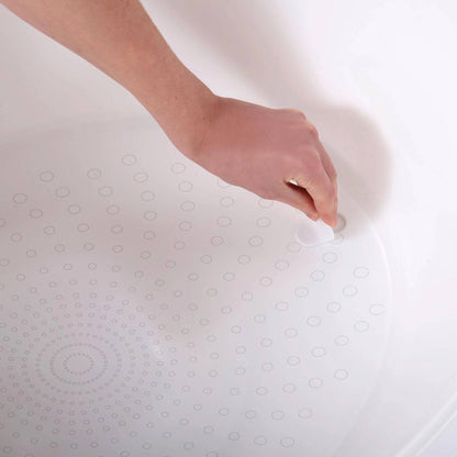 Close-up of a hand touching the textured, non-slip surface at the bottom of the Shnuggle bath, showing the circular grip pattern.