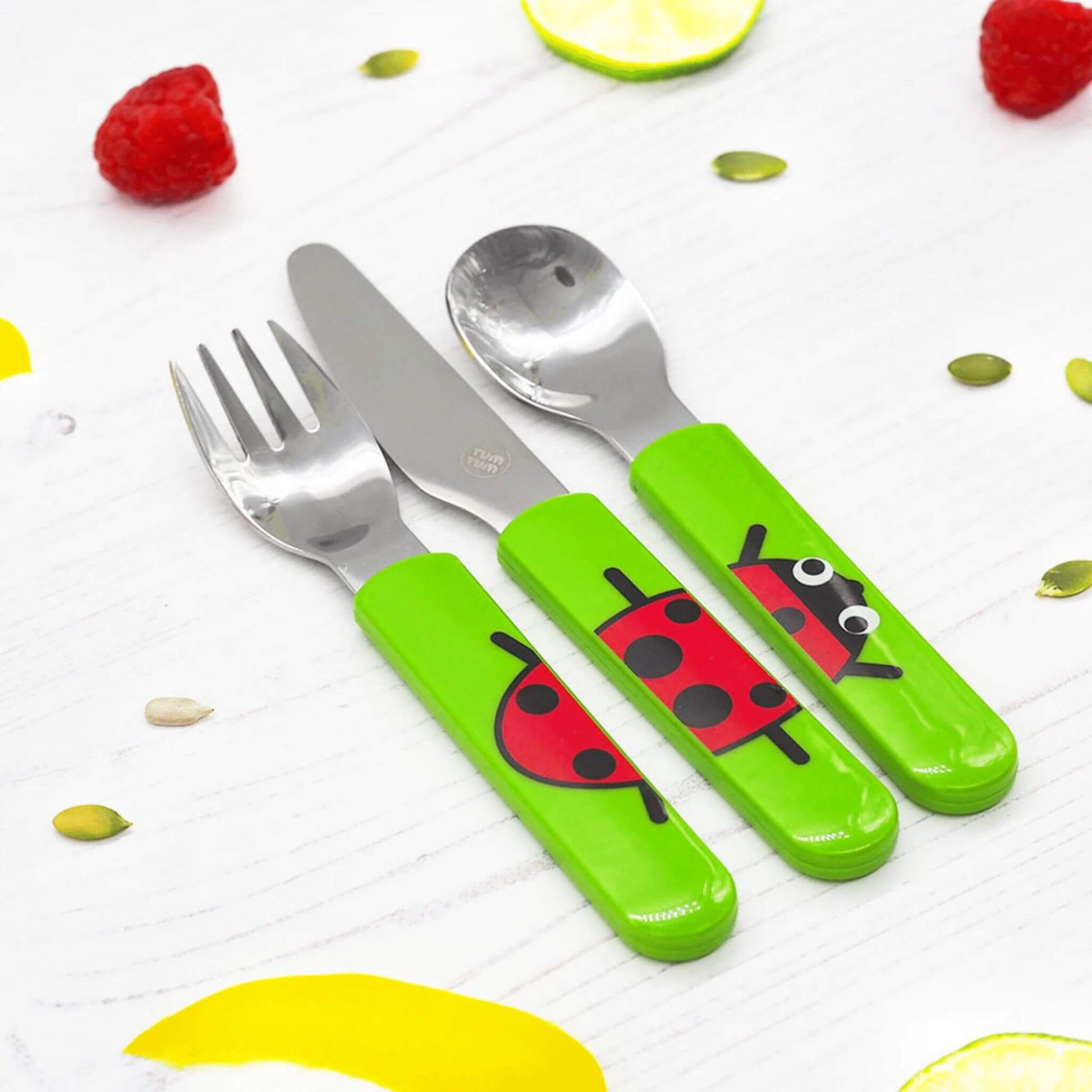 The TUM TUM Easy Scoop Cutlery Set, featuring a spoon, knife, and fork with bright green handles and a cute ladybird design. Designed for easy self-feeding.