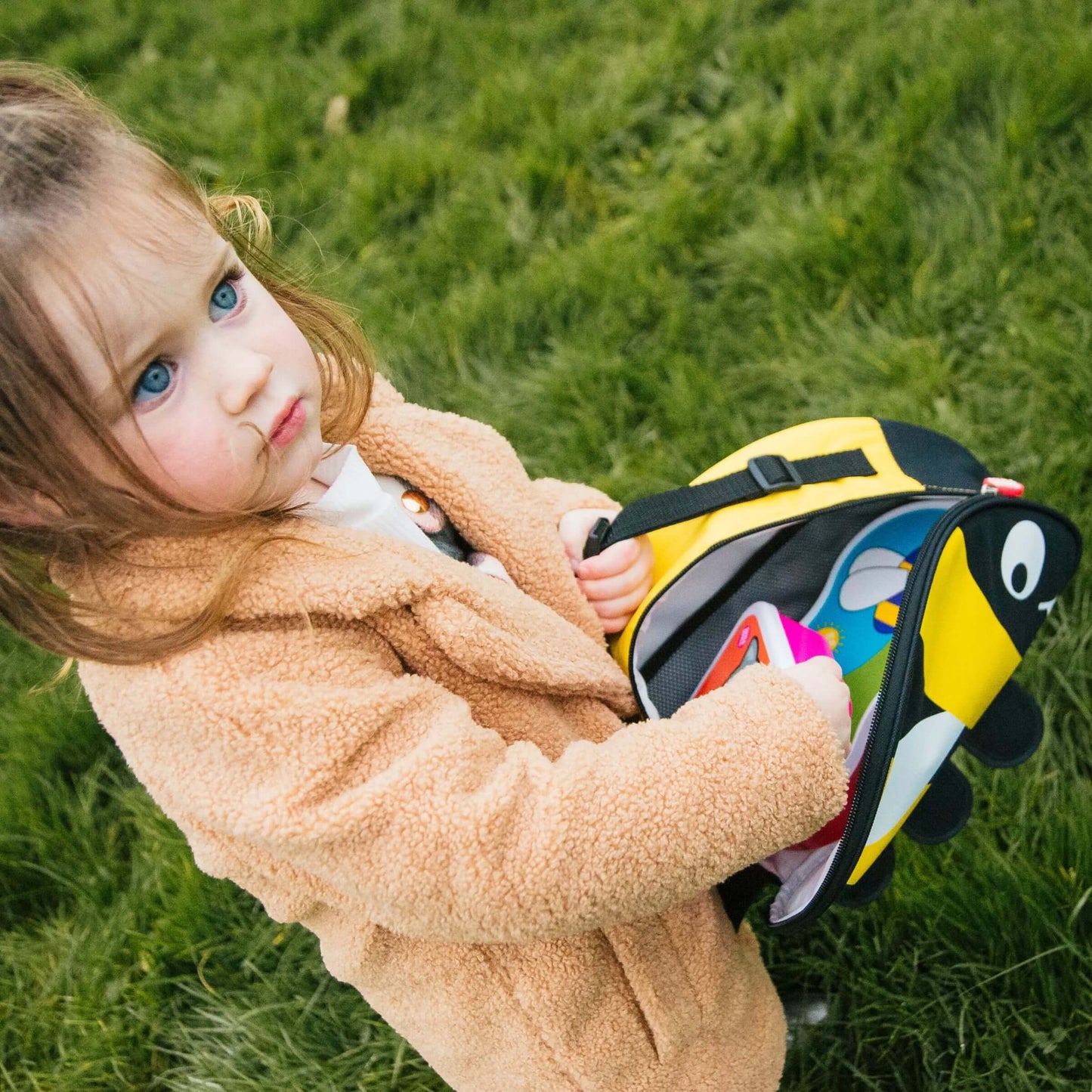 A child carrying the TUM TUM bee design insulated lunch bag,with matching snack containers inside, perfect for school or outdoor adventures.