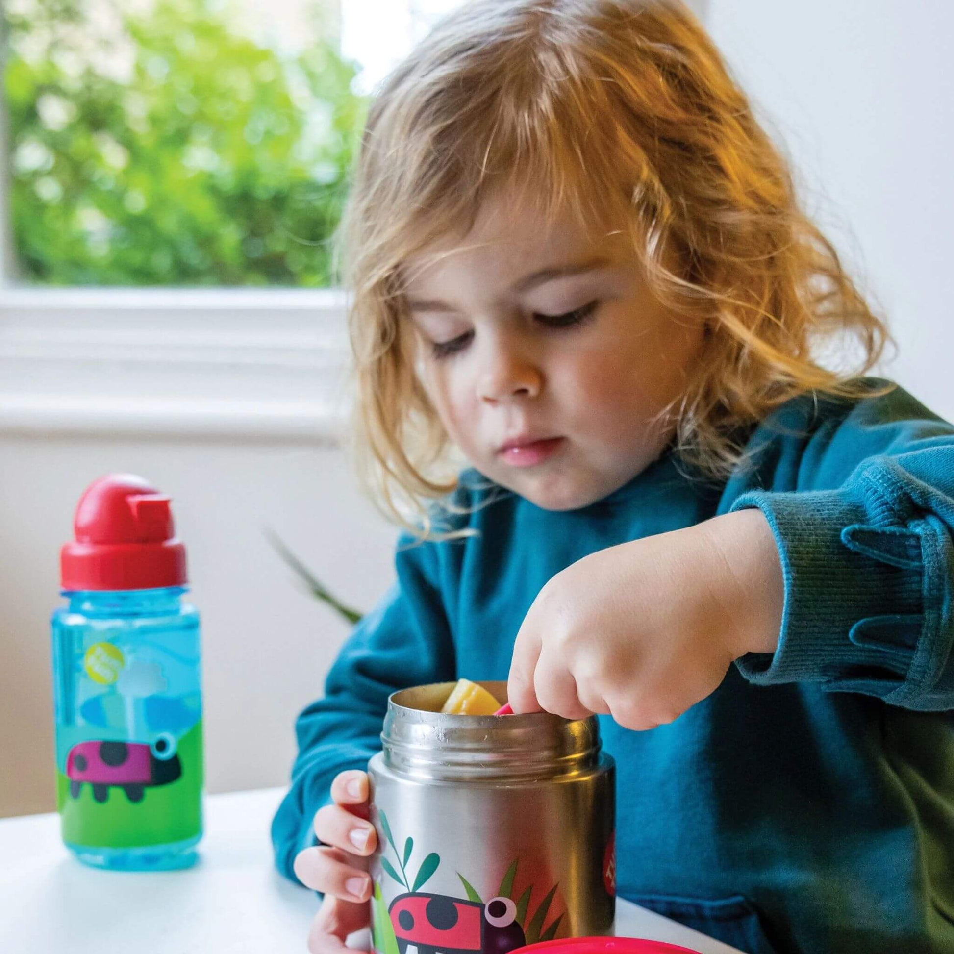 Child eating from a TUM TUM insulated food flask, with a red spork. Perfect for hot or cold meals.