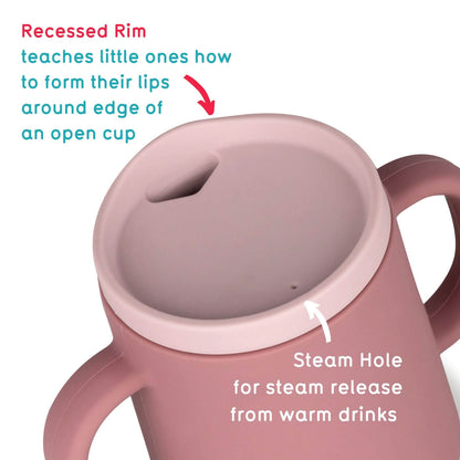 A pink TUM TUM silicone sippy cup with a recessed rim designed to help toddlers learn to form their lips around the edge of an open cup. It features a steam hole for safe steam release from warm drinks, ensuring comfort and safety during use.