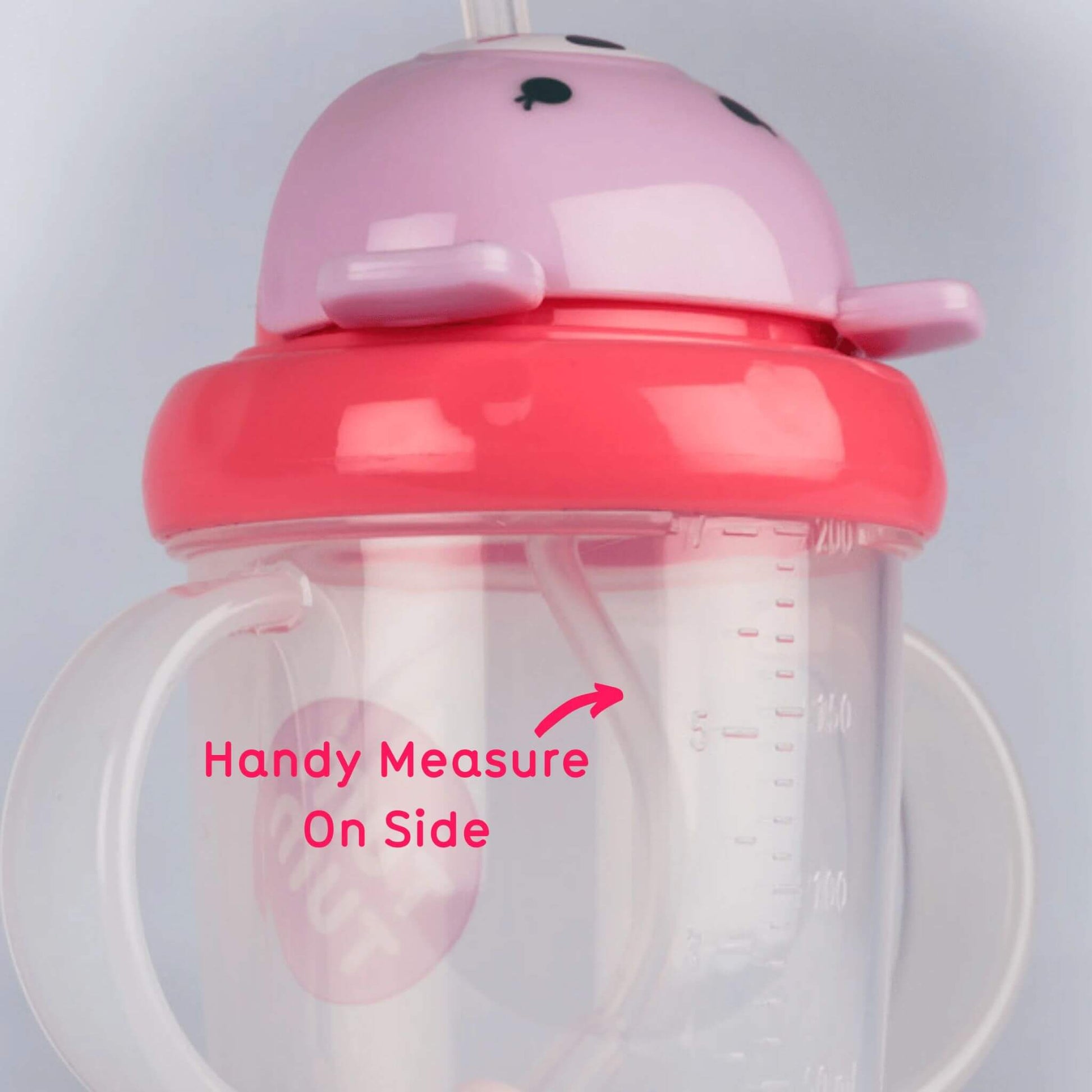 A close-up of the TUM TUM Tippy Up Cup, featuring a Betsy bear lid and dual handles. The cup shows a handy measurement scale on the side for easy tracking of fluid intake. The weighted straw inside follows the liquid for smooth, any-angle drinking.