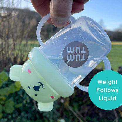 A TUM TUM Tippy Up Cup featuring a polar bear lid with two clear handles, shown being tipped upside down. The weighted straw inside follows the liquid, making it easy for toddlers to drink from any angle. The BPA-free design ensures safety and spill-free drinking while on the go.