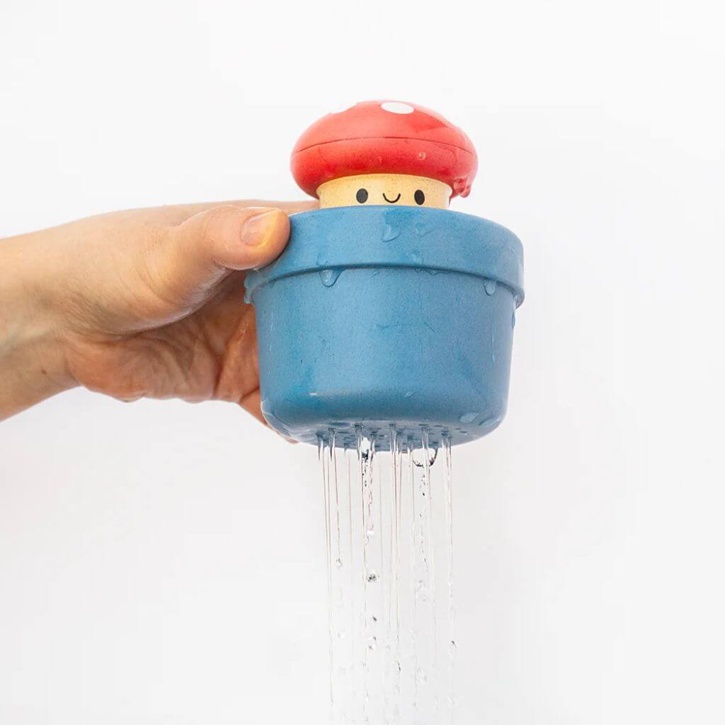 Hand holding the Tiger Tribe pop-up mushroom bath toy, with water streaming from the base, ideal for fun and sensory bath play for toddlers.