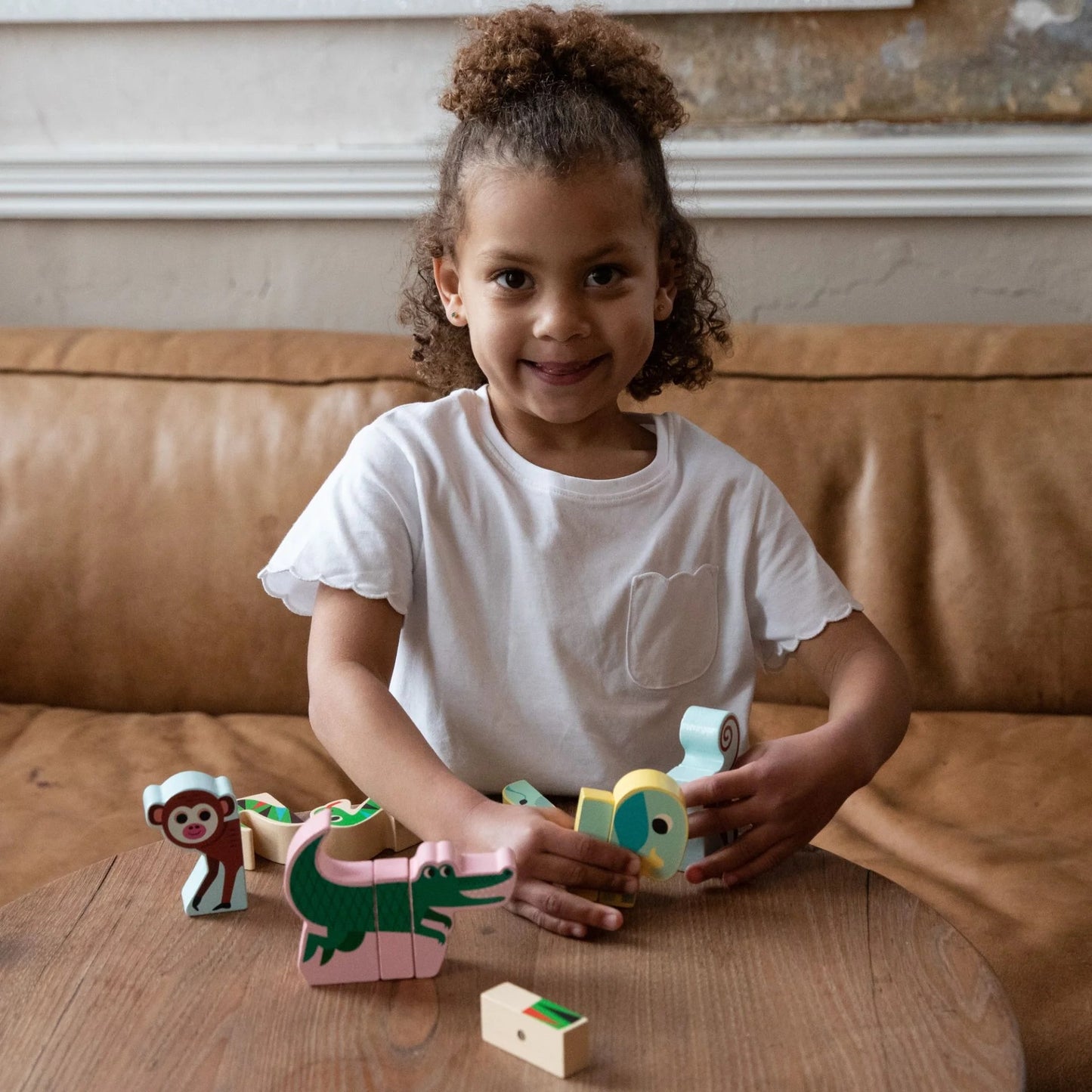 Smiling child proudly displaying her Vilac Magnetic Jungle Animals creation, showing educational wooden toys for preschoolers.