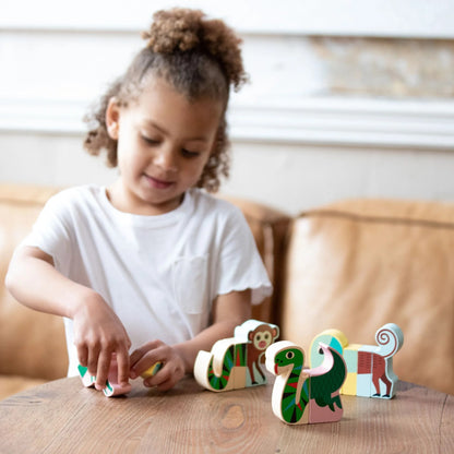 Young girl arranging Vilac Magnetic Jungle Animals wooden blocks on table, demonstrating hands-on learning with sustainable toys.