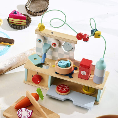 Vilac wooden kitchen playset in baking scene with wooden pastries, fruit bead maze, sink and cooktop for imaginative play.