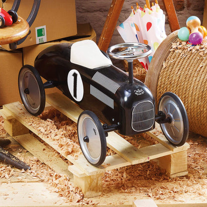 Vilac Classic Metal Car in black with white seat, vintage design, displayed on wood shavings, perfect for little drivers and imaginative play.