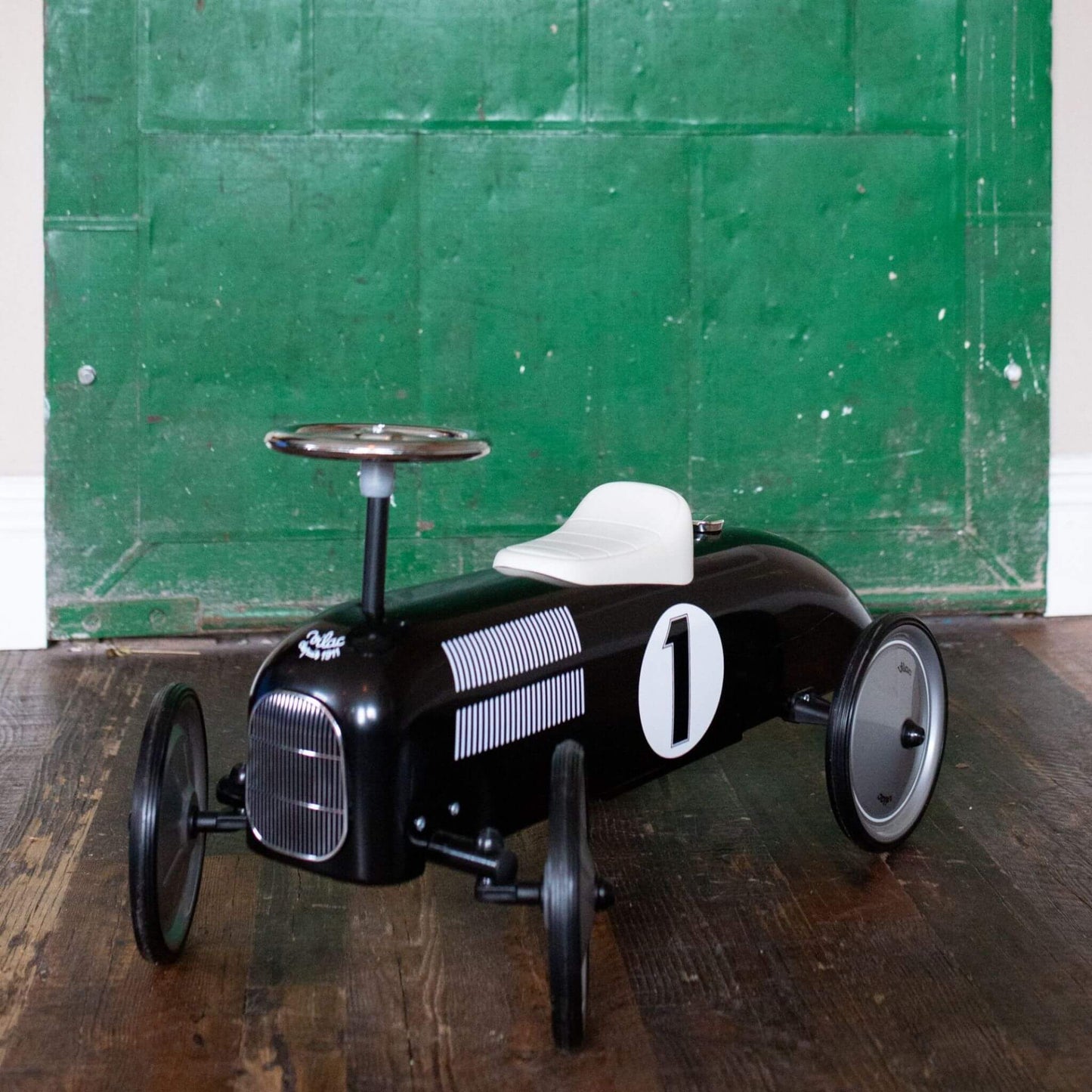 Vilac Classic Metal Car in black with white seat, retro design, featuring number 1 detail, set against a rustic green backdrop.