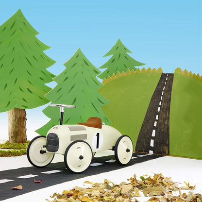 Vilac Classic Metal Car in off-white with a brown seat, silver steering wheel, and number 1 detail, displayed in a illustrated forest road setting.