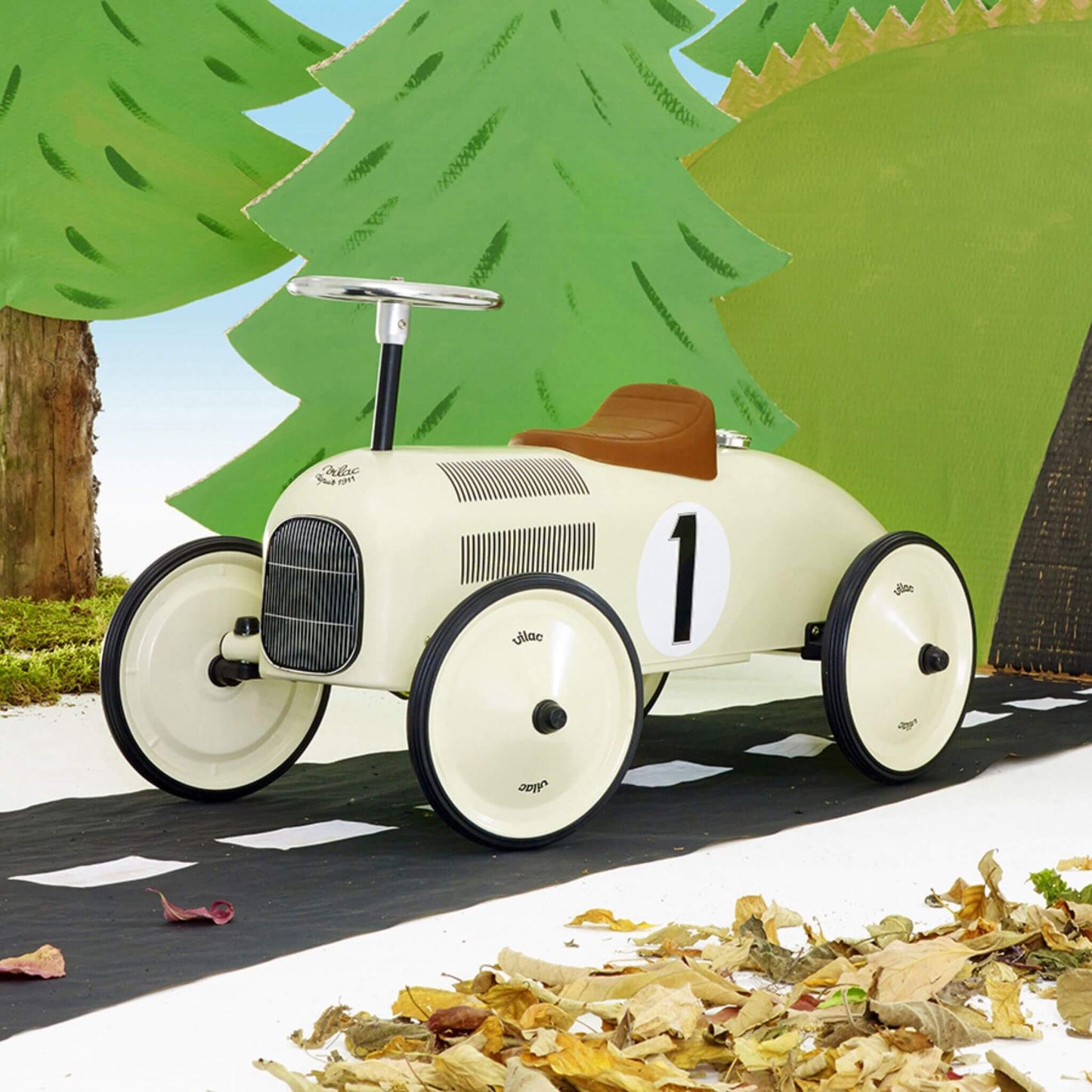 Vilac Classic Metal Car in off-white with a brown seat and number 1 detail, showcased on a road surrounded by cartoon forest scenery.