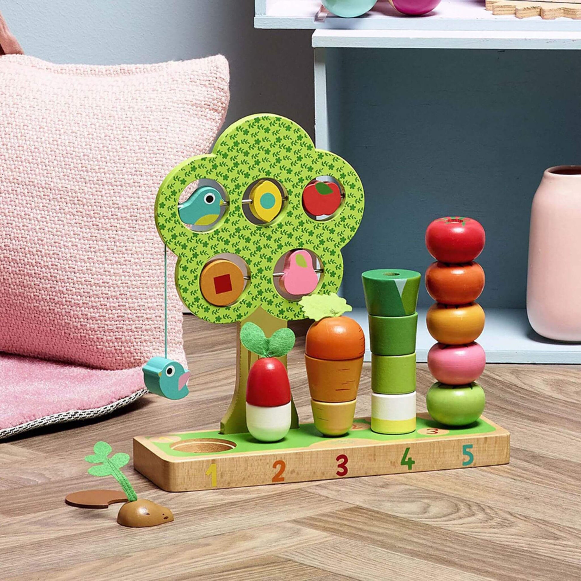 Vilac I Learn Counting Vegetables game displayed in a playroom setting, featuring a colourful wooden stacking base, vegetables, rotating fruits, and a hanging bird.