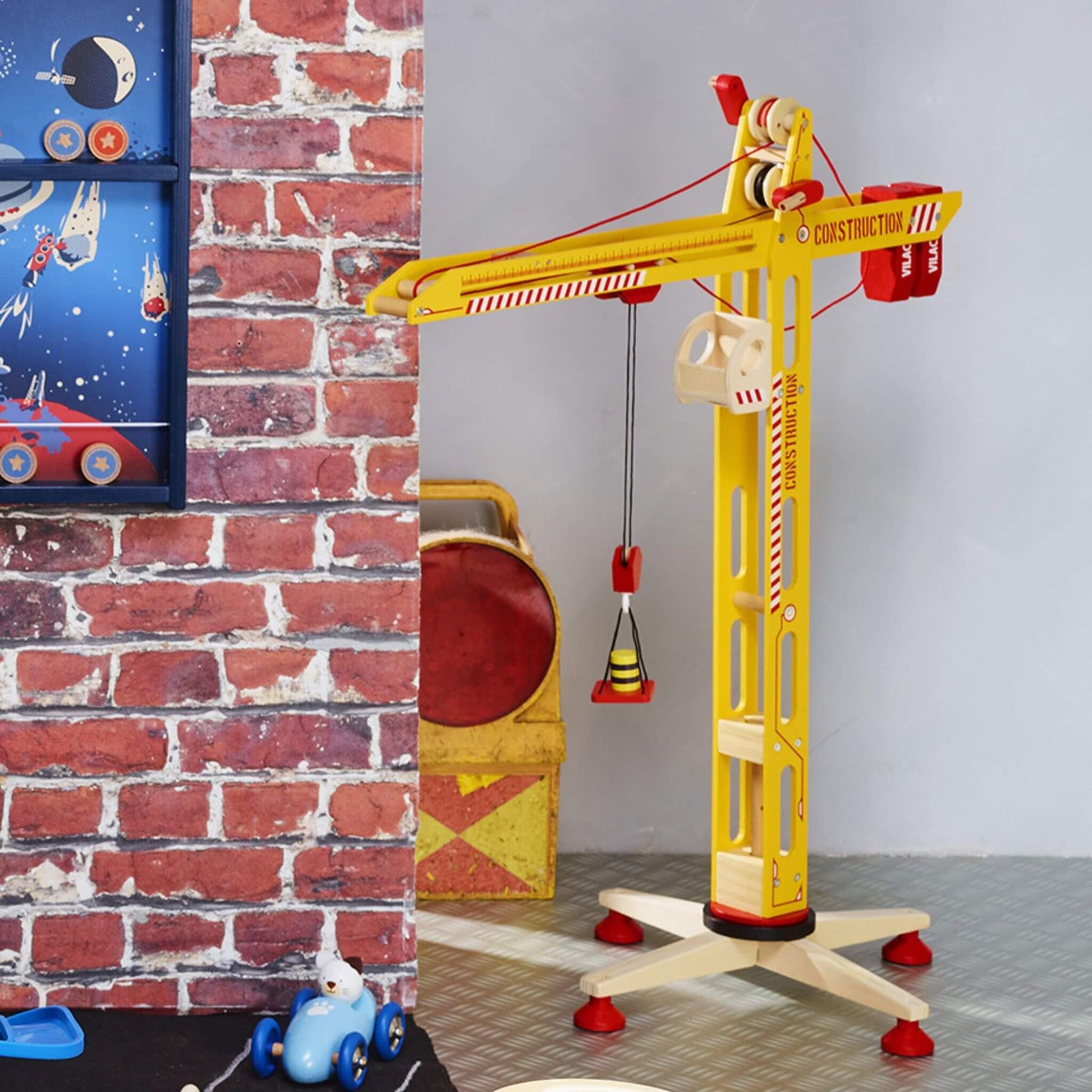 Vilac large yellow wooden crane set against a fun brick and space-themed background, perfect for imaginative construction play.