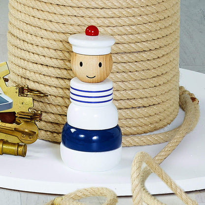 Vilac Sailor Stacking Toy displayed on a nautical-themed setup with coiled rope and brass accessories, featuring its wooden sailor design.