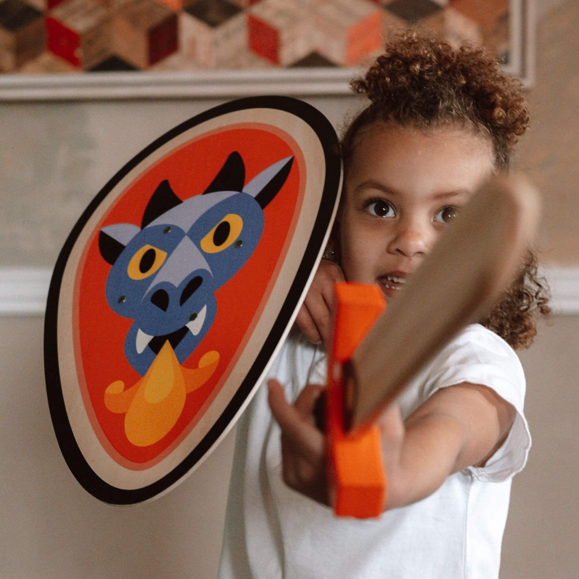 A child holding a Vilac dragon-themed wooden shield and sword, ready for imaginative adventures and playful battles at home.