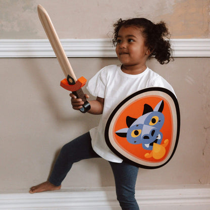 A child posing with a Vilac dragon-themed wooden sword and shield, ready for imaginative knightly adventures and playful storytelling.