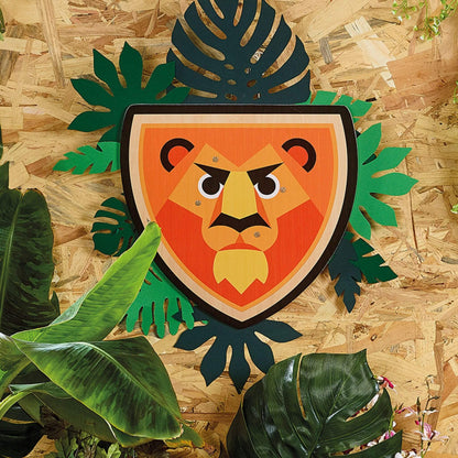 A wooden lion-themed shield displayed against a backdrop of lush green leaves, evoking a jungle-inspired scene perfect for imaginative adventures.